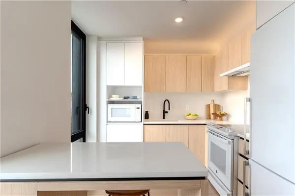 a kitchen with kitchen island a sink a stove and white cabinets