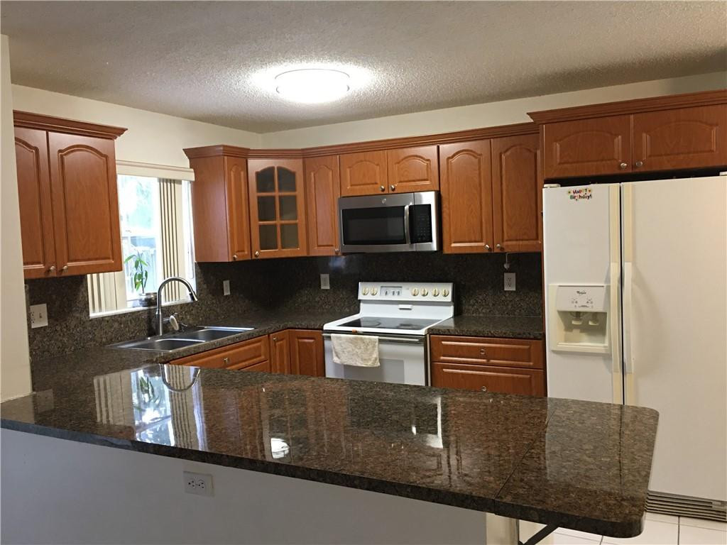 8422 Southwest 44th Place Davie, FL 33328 - Photo 2 of 16 a kitchen with kitchen island a stove a sink and a refrigerator