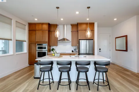 a kitchen with a table chairs refrigerator and wooden floor