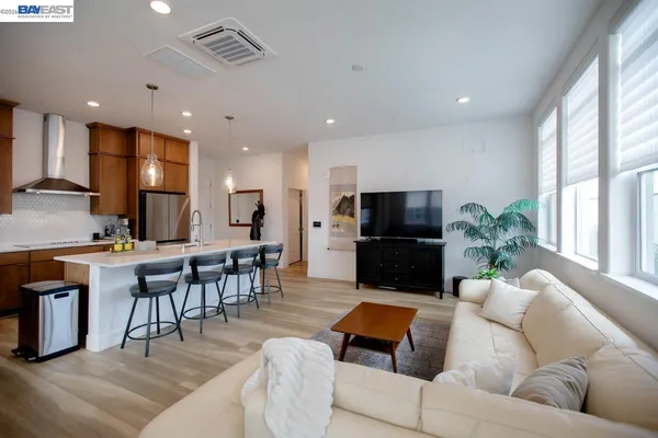 a kitchen with stainless steel appliances a refrigerator a stove a dining table and chairs with wooden floor