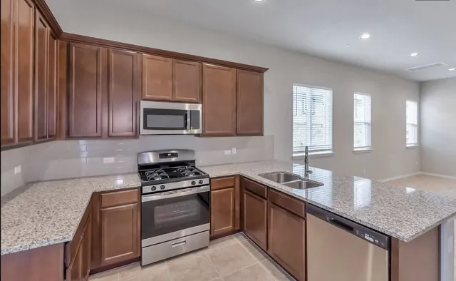 a kitchen with granite countertop stainless steel appliances a stove sink and microwave