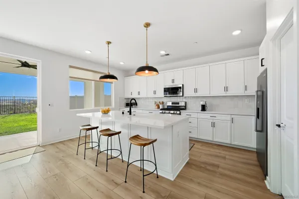 a kitchen with kitchen island granite countertop wooden floors and white cabinets