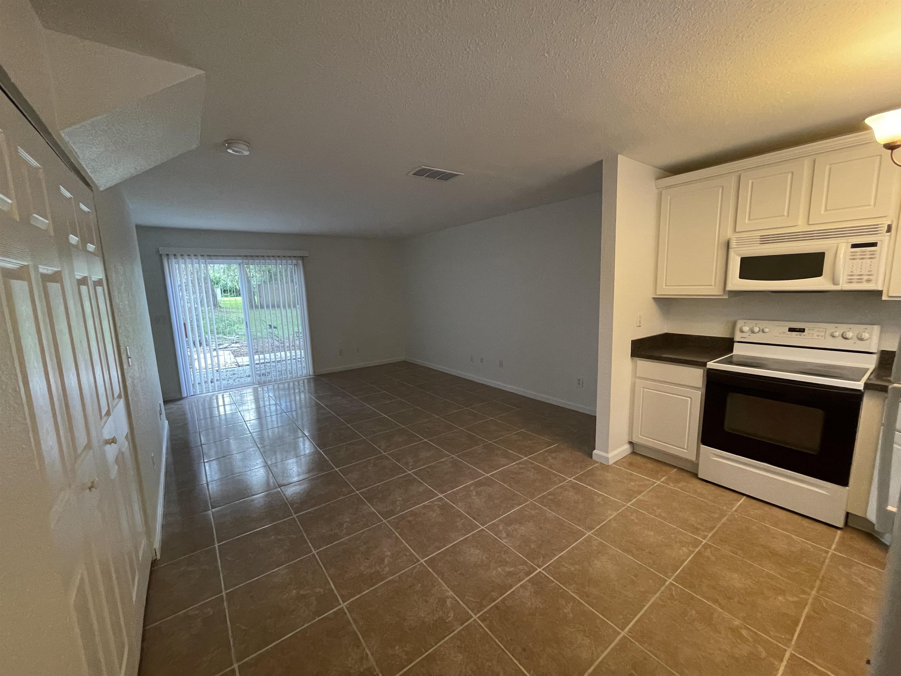 4420 Carter Road, Unit 60 St. Augustine, FL 32086 - Photo 3 of 14 a kitchen with granite countertop a stove a microwave and a refrigerator