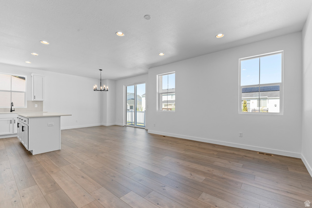 3016 West 2650 North Clinton, UT 84015 - Photo 20 of 20 Kitchen featuring white cabinetry, plenty of natural light, suspended lighting, and open floor plan