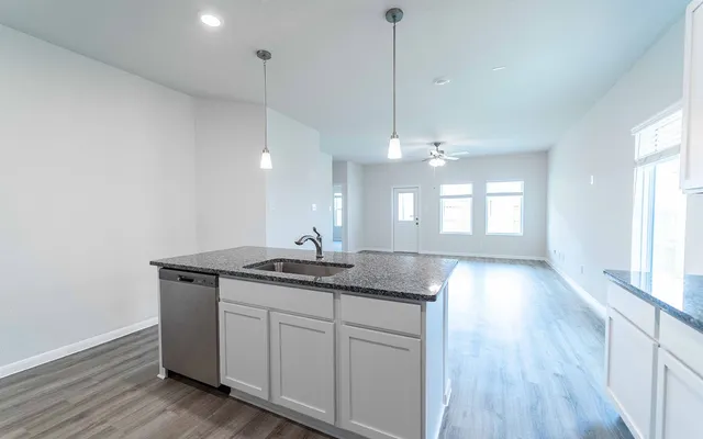 a kitchen with granite countertop a sink a window and wooden floor