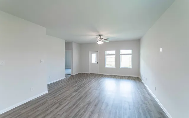 a view of an empty room with wooden floor and window