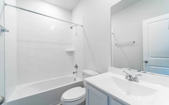 a bathroom with a bathtub shower sink vanity mirror and toilet