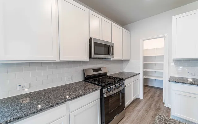 a kitchen with granite countertop a sink and a stove top oven