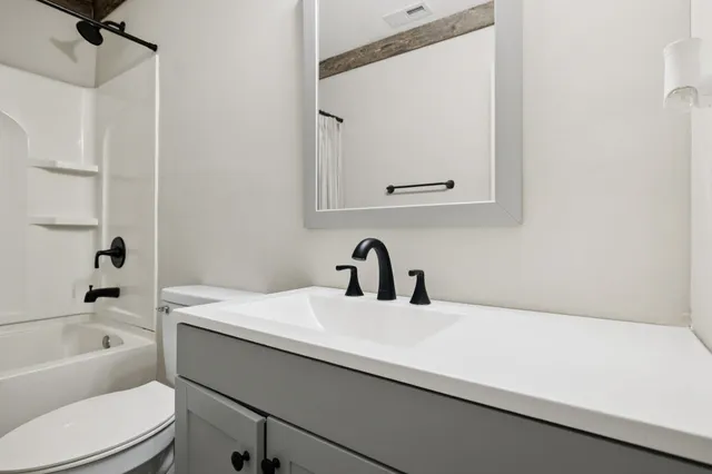 a bathroom with a bathtub sink vanity mirror and toilet