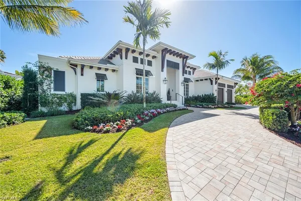a front view of a house with a yard and potted plants