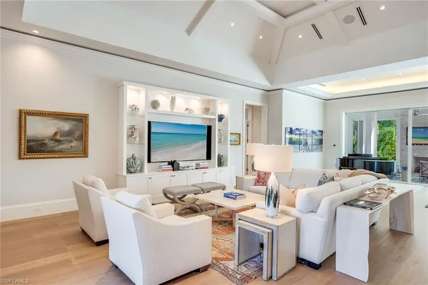 a living room with furniture a flat screen tv and floor to ceiling window