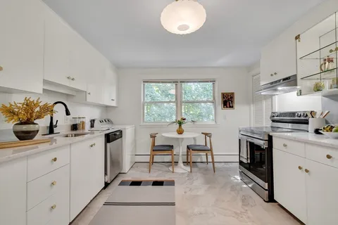 a kitchen with a sink white cabinets and white appliances