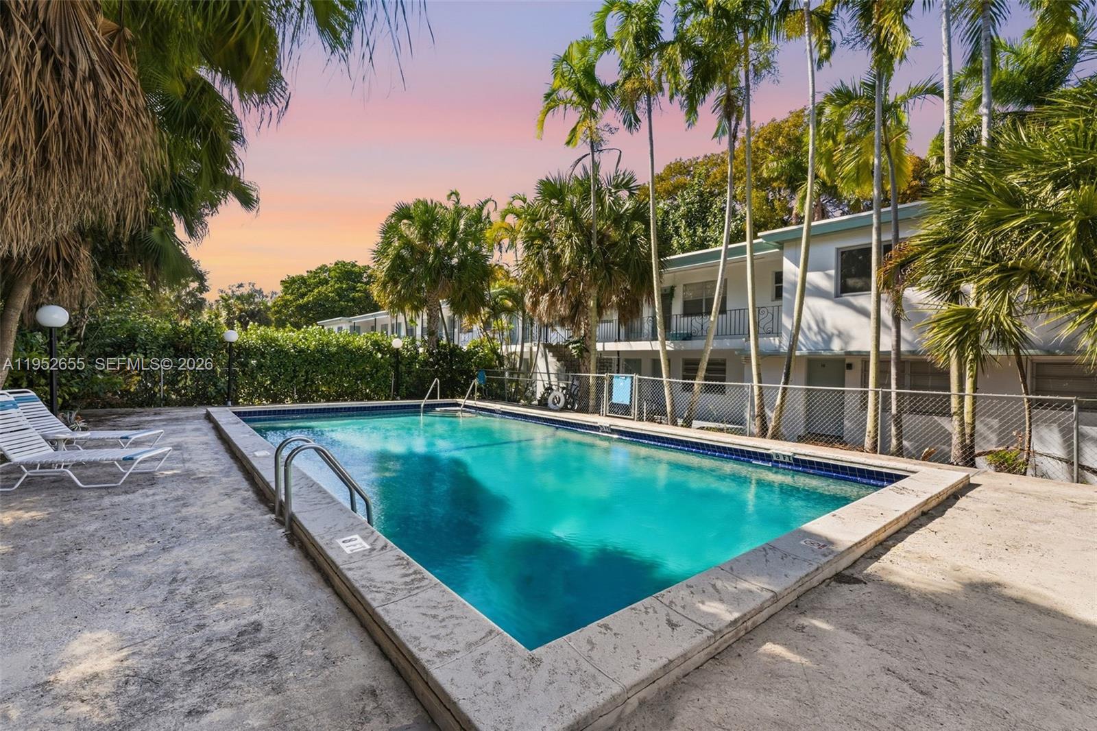645 Northeast 77th Street, Unit 17 Miami, FL 33138 - Photo 9 of 12 a view of a swimming pool with a yard and palm trees