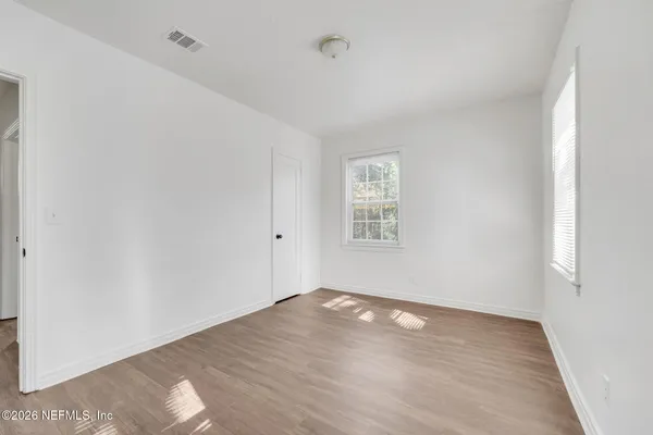 an empty room with wooden floor and windows