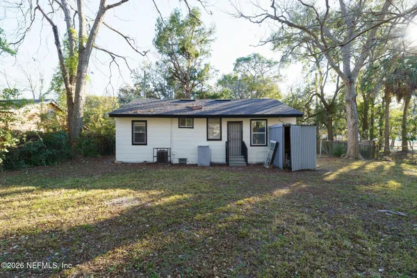 a view of a house with a yard and large tree