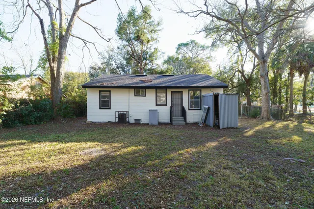 a view of a house with a yard and large tree