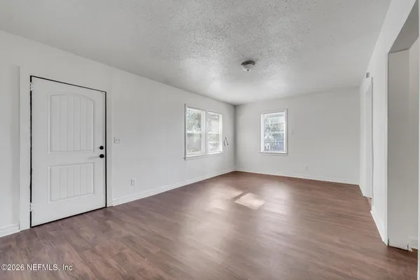 an empty room with wooden floor and windows