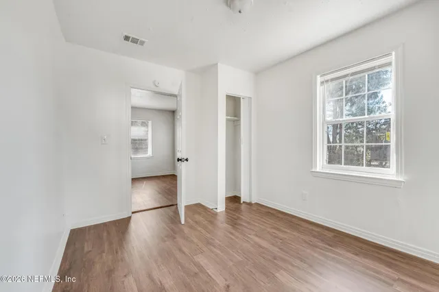 an empty room with wooden floor and windows