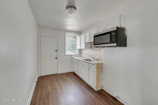 a kitchen with granite countertop a stove top oven a sink and dishwasher with wooden floor