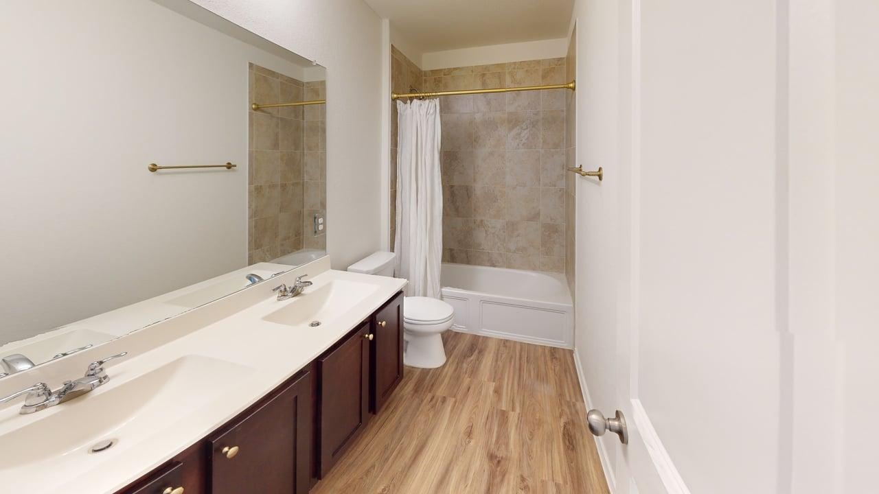1000 Berryhack Court Hutto, TX 78634 - Photo 16 of 22 Bathroom featuring double vanity, shower / tub combo with curtain, and light wood-type flooring