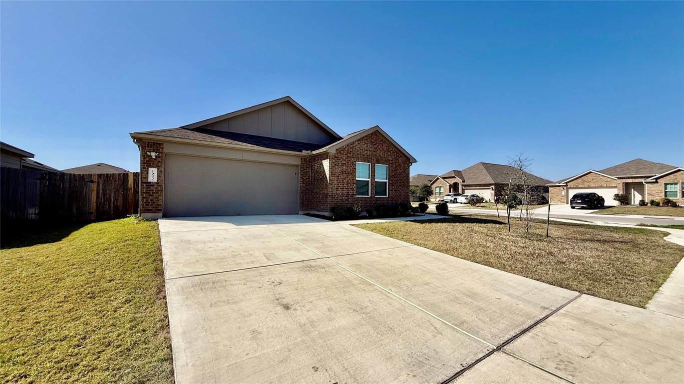 1000 Berryhack Court Hutto, TX 78634 - Photo 2 of 22 View of front of property with concrete driveway, brick siding, board and batten siding, an attached garage, and a residential view