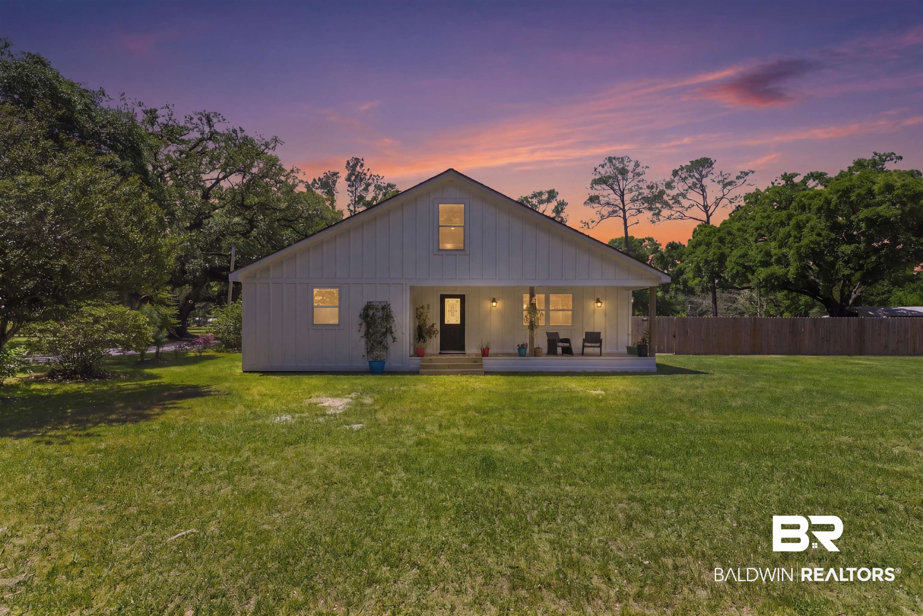 6447 Bemis Lane Bon Secour, AL 36511 - Photo 4 of 62 Modern farmhouse exterior featuring board and batten siding, an inviting covered front porch, a dark entry door, and a spacious green lawn