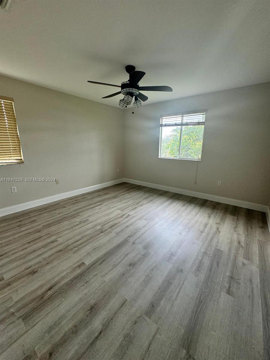 4527 Southwest 129th Avenue Miramar, FL 33027 - Photo 16 of 28 an empty room with wooden floor ceiling fan and windows