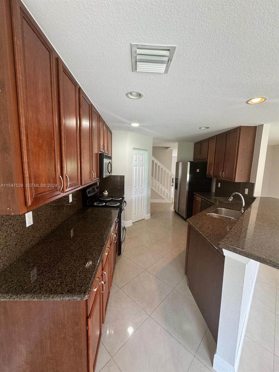 4527 Southwest 129th Avenue Miramar, FL 33027 - Photo 4 of 28 a kitchen with a sink and a refrigerator