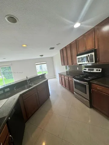 a kitchen with stainless steel appliances granite countertop a stove a sink and a refrigerator
