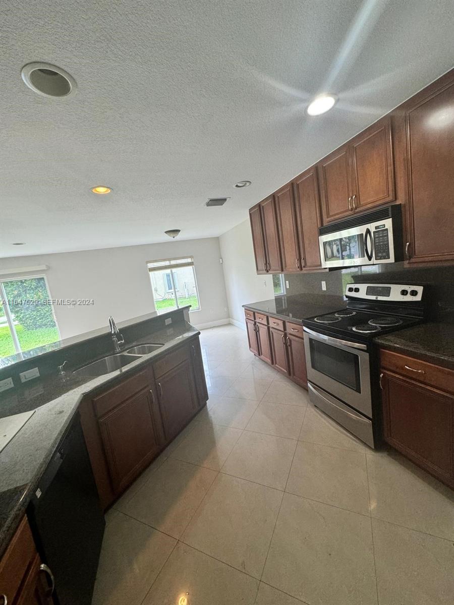4527 Southwest 129th Avenue Miramar, FL 33027 - Photo 5 of 28 a kitchen with stainless steel appliances granite countertop a stove a sink and a refrigerator