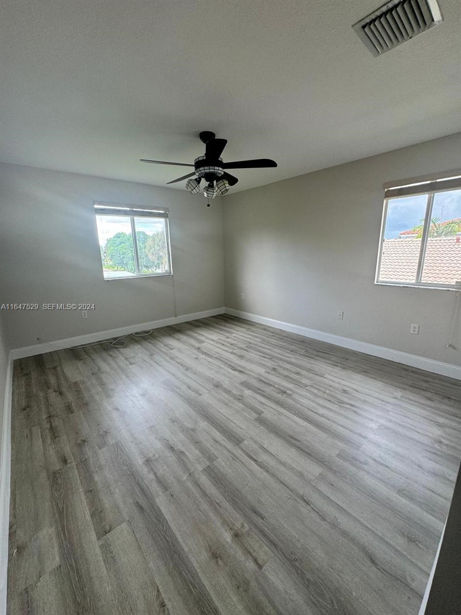 4527 Southwest 129th Avenue Miramar, FL 33027 - Photo 7 of 28 an empty room with wooden floor fan and windows