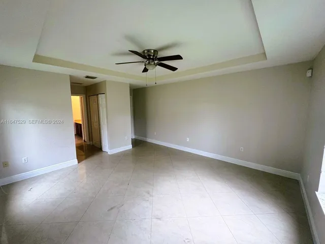 an empty room with a ceiling fan and carpet