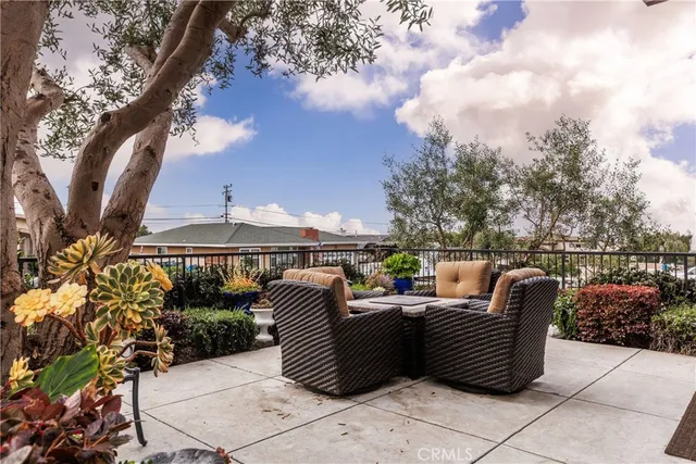 a view of a patio with couches plants and large trees