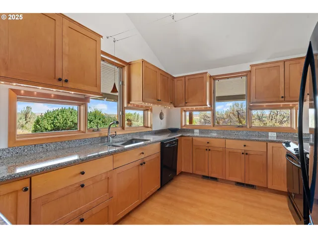 a kitchen with granite countertop a sink window and cabinets