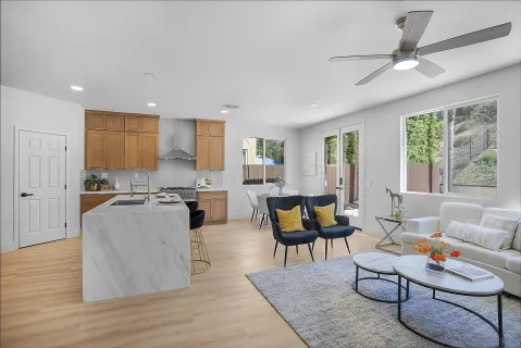 a living room with furniture kitchen view and a wooden floor