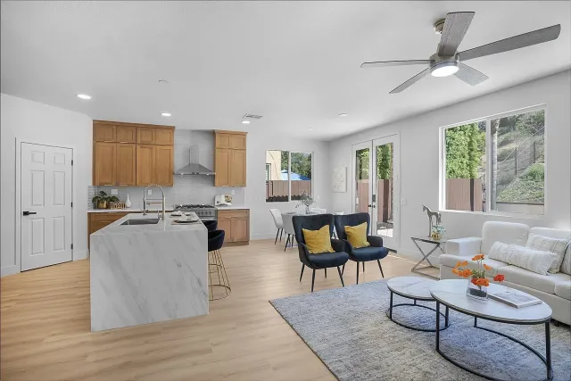 a living room with furniture kitchen view and a wooden floor