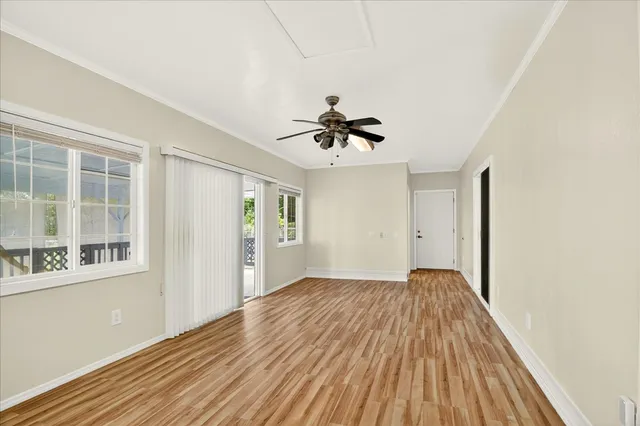 a view of empty room with wooden floor and fan