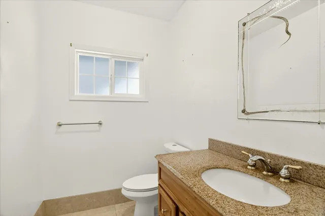 a bathroom with a granite countertop sink toilet and mirror