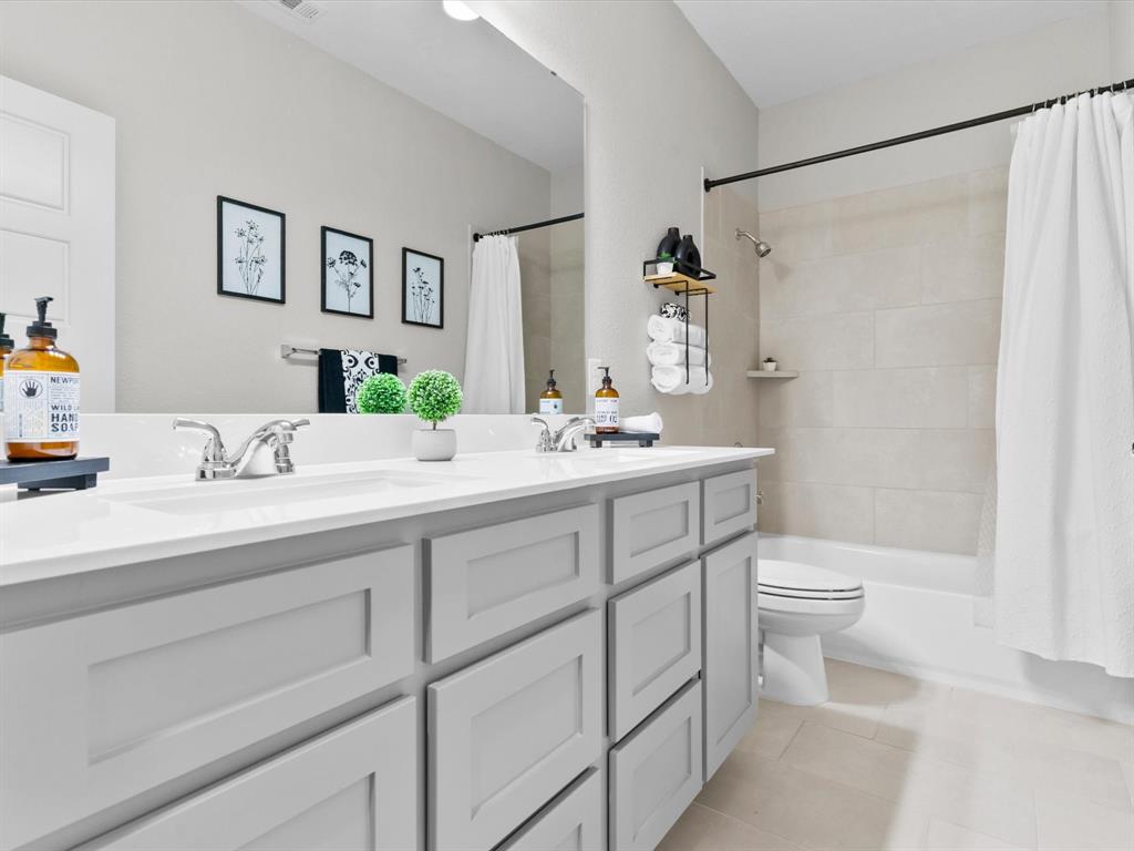 112 Pecan Court Rhome, TX 76078 - Photo 27 of 38 Bathroom with double vanity, shower / bath combo with shower curtain, and light tile patterned flooring