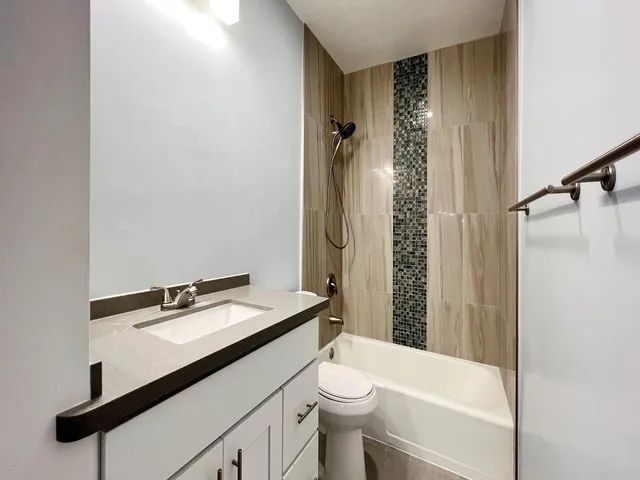 a bathroom with a sink a toilet a mirror and shower