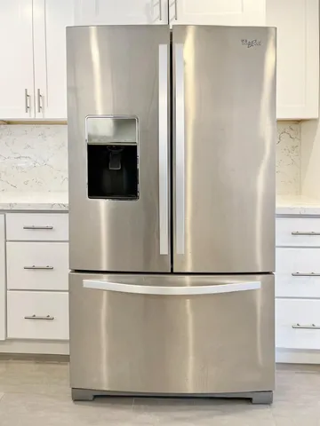a close view of a refrigerator in kitchen with stainless steel appliances granite countertop a refrigerator and a stove