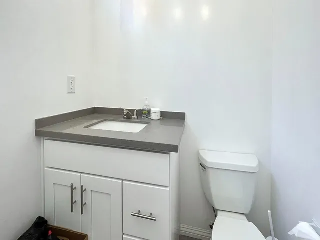 a bathroom with a granite countertop toilet and sink