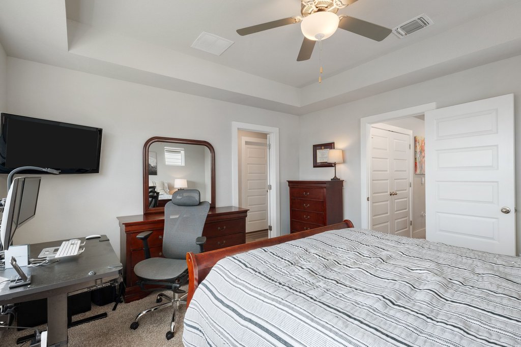 7403 Travertine Spring Drive, Unit 117 Austin, TX 78744 - Photo 26 of 37 Comfortable bedroom offers a tray ceiling and a ceiling fan, perfect for relaxation or a home office setup.