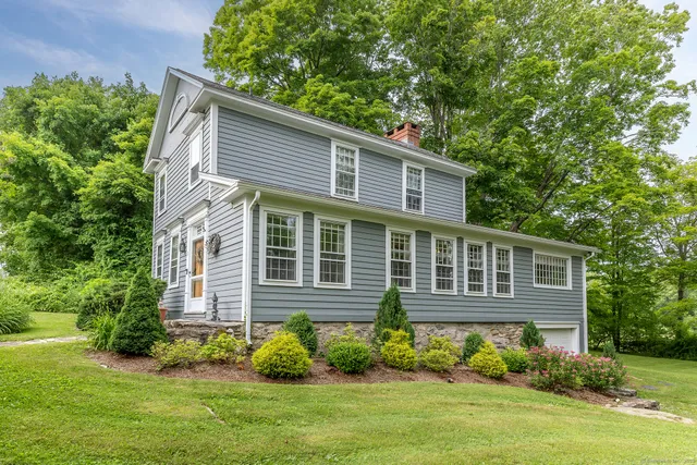 a brick house with a yard potted plants and large tree