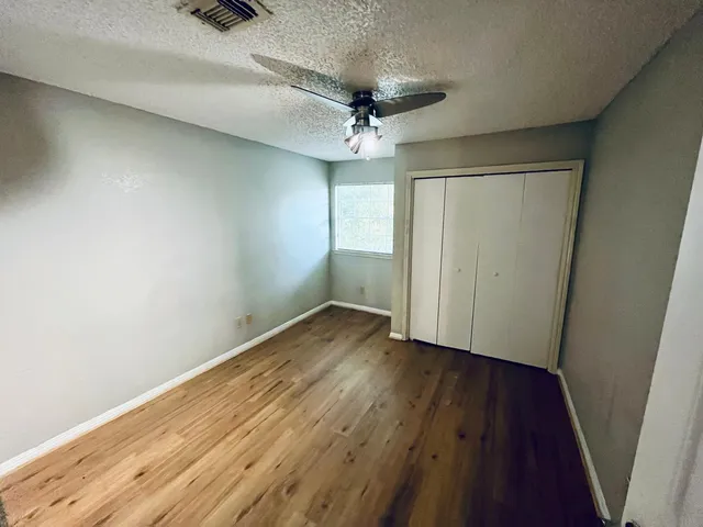 an empty room with wooden floor and a ceiling fan