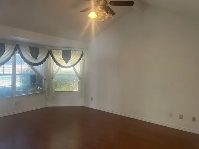 an empty room with a chandelier fan and windows