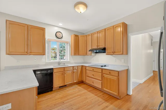 a kitchen with stainless steel appliances granite countertop a stove a sink and a refrigerator with wooden floors