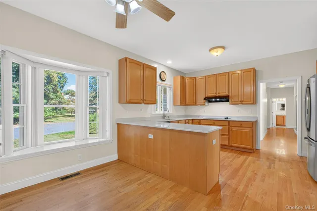 a large kitchen with stainless steel appliances granite countertop a stove a sink dishwasher and a large refrigerator with wooden floor