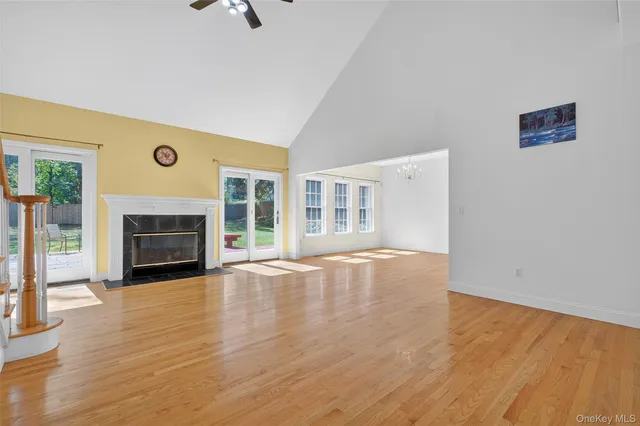 a view of an empty room with wooden floor fireplace and a window