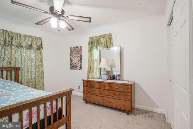 a bedroom with a bed a dresser and potted plants on the table